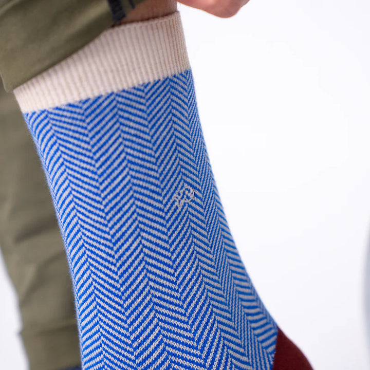 Blue and white herringbone patterned sock on a person's foot with a blurred background
