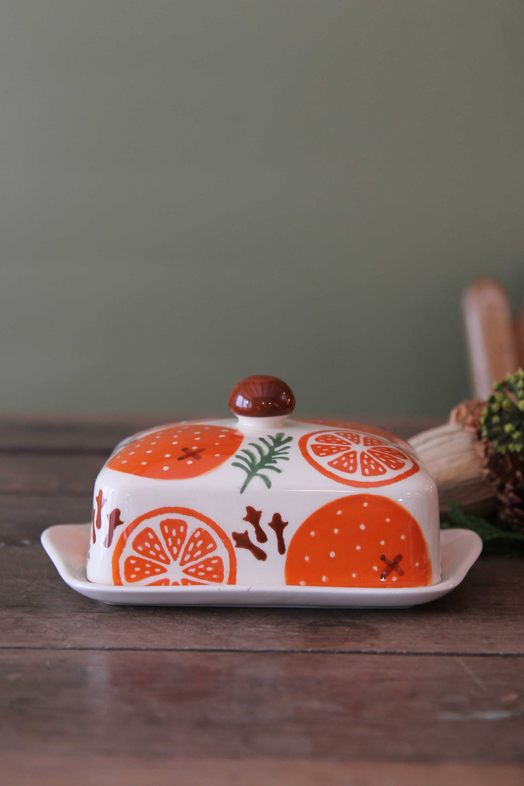 Butter dish with orange design on a wooden surface