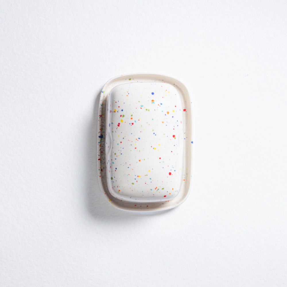 White hairbrush with colorful speckles on a light gray background