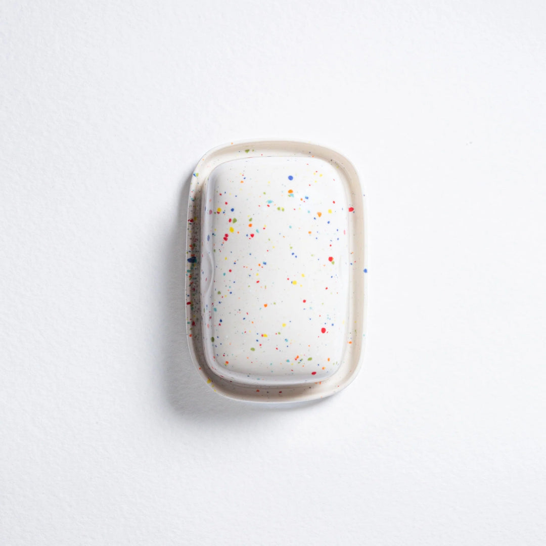 White hairbrush with colorful speckles on a light gray background