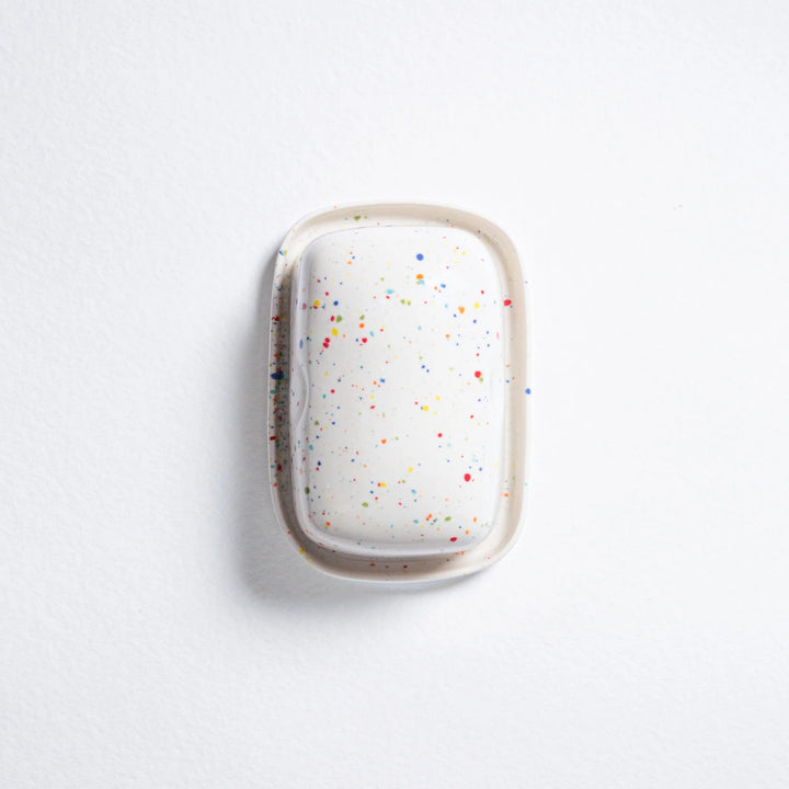 White hairbrush with colorful speckles on a light gray background