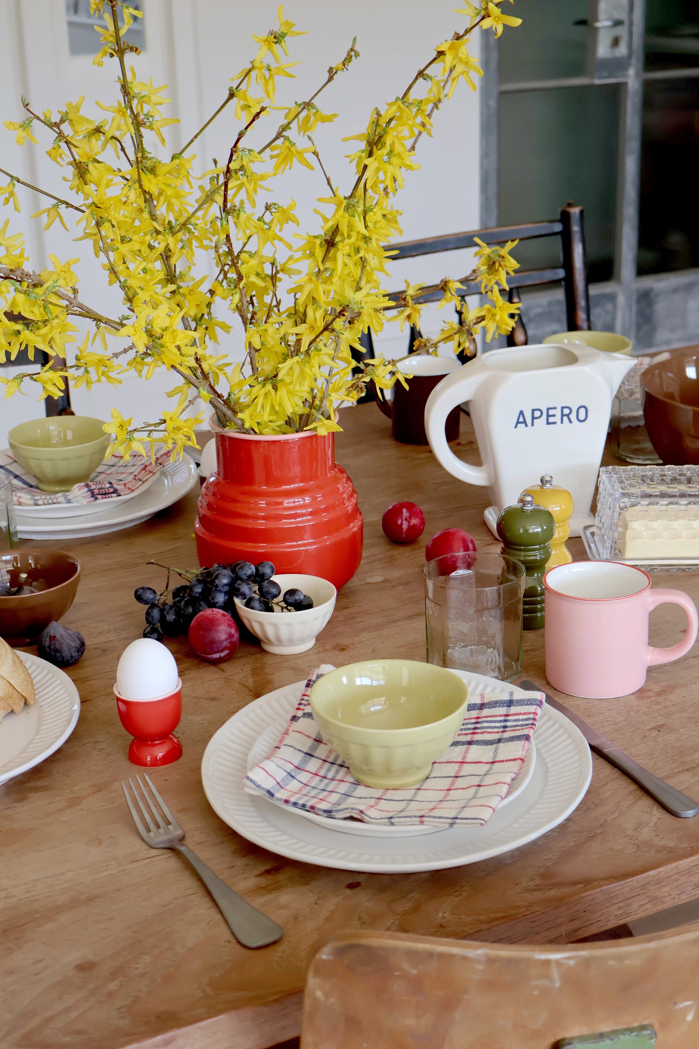 Dining table set with a vase of yellow flowers, plates, and cutlery.