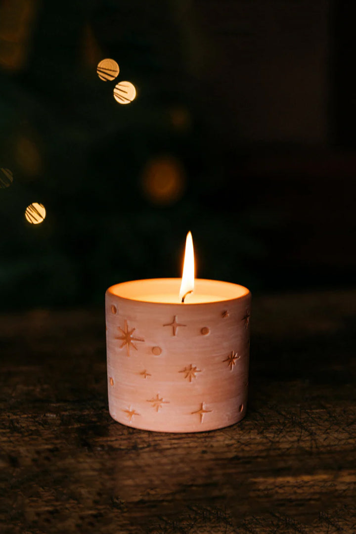 Candle in a decorative holder with a blurred Christmas tree in the background