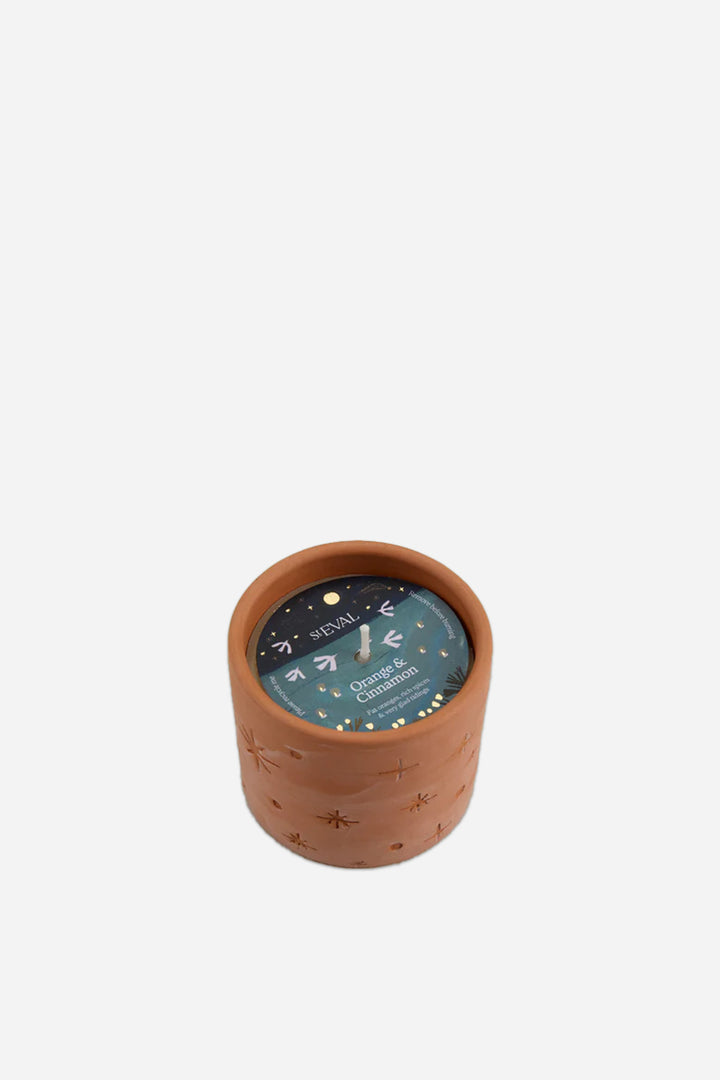 Terracotta orange and cinnamon candle with a dark green label on a white background