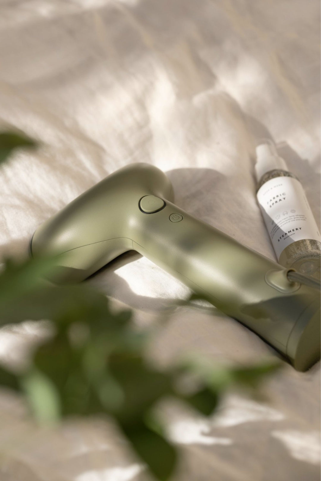 green hand held steamer on bed