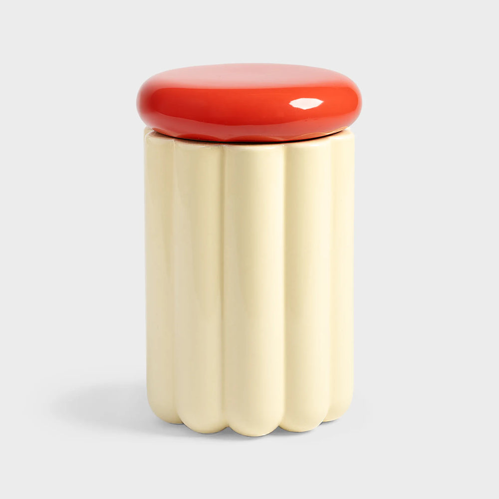cream cylindrical container with a red lid 