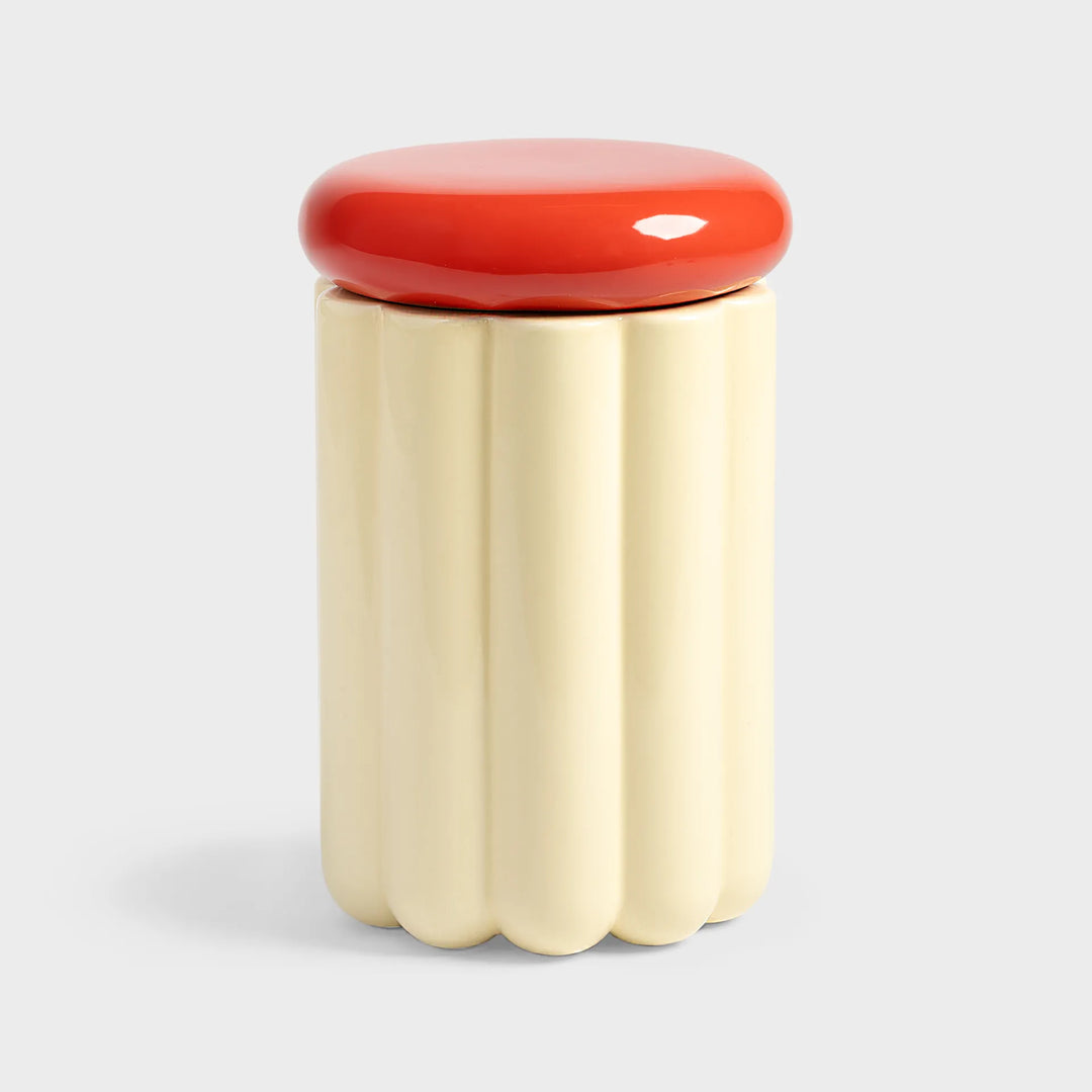 cream cylindrical container with a red lid 