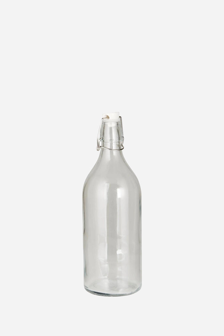 A clear glass swing-top bottle with a metal clasp closure, shown against a plain light gray background.