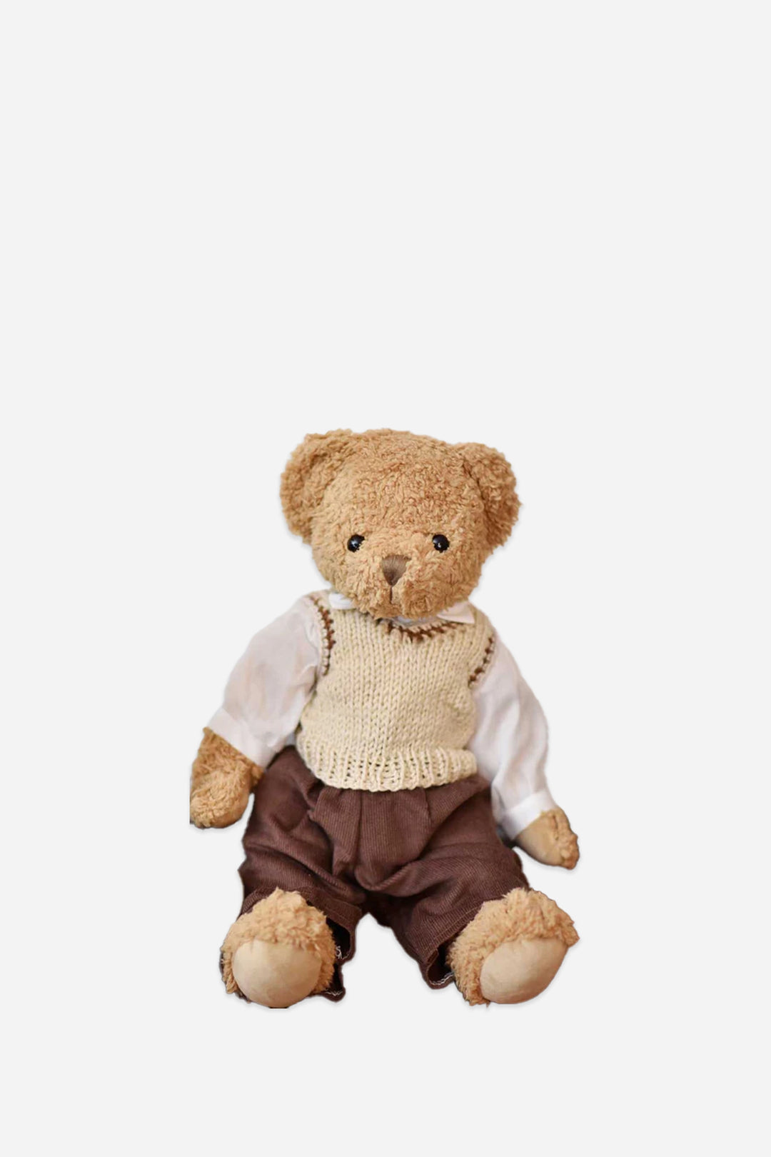 Teddy bear wearing a knitted vest and brown pants on a white background