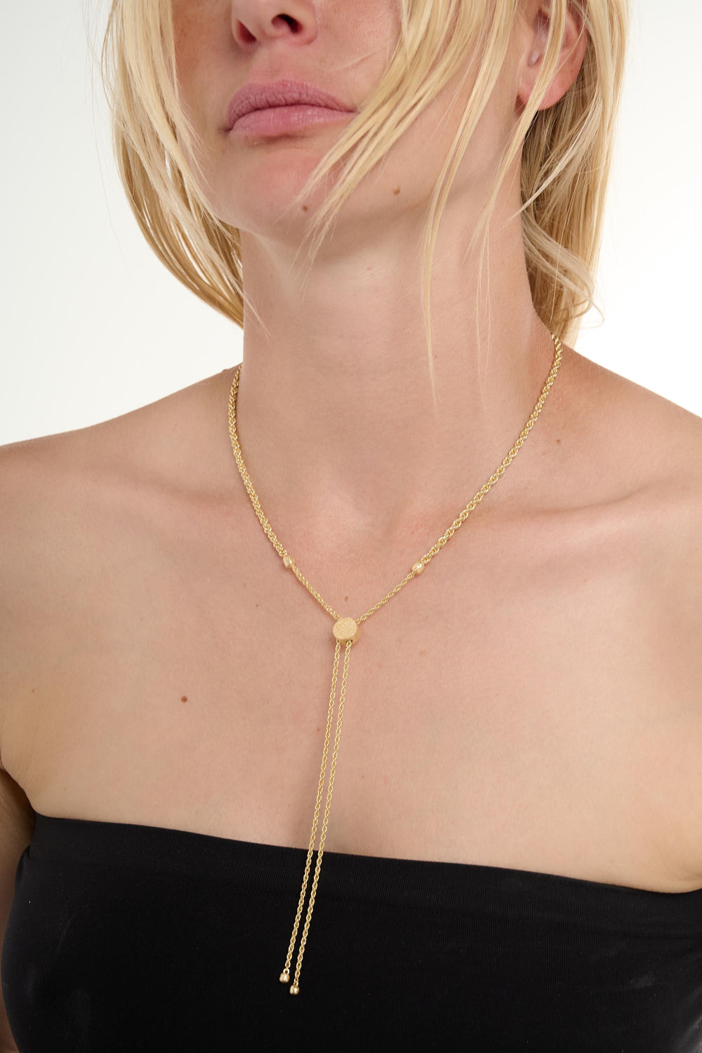 Gold necklace worn by a person on a white background