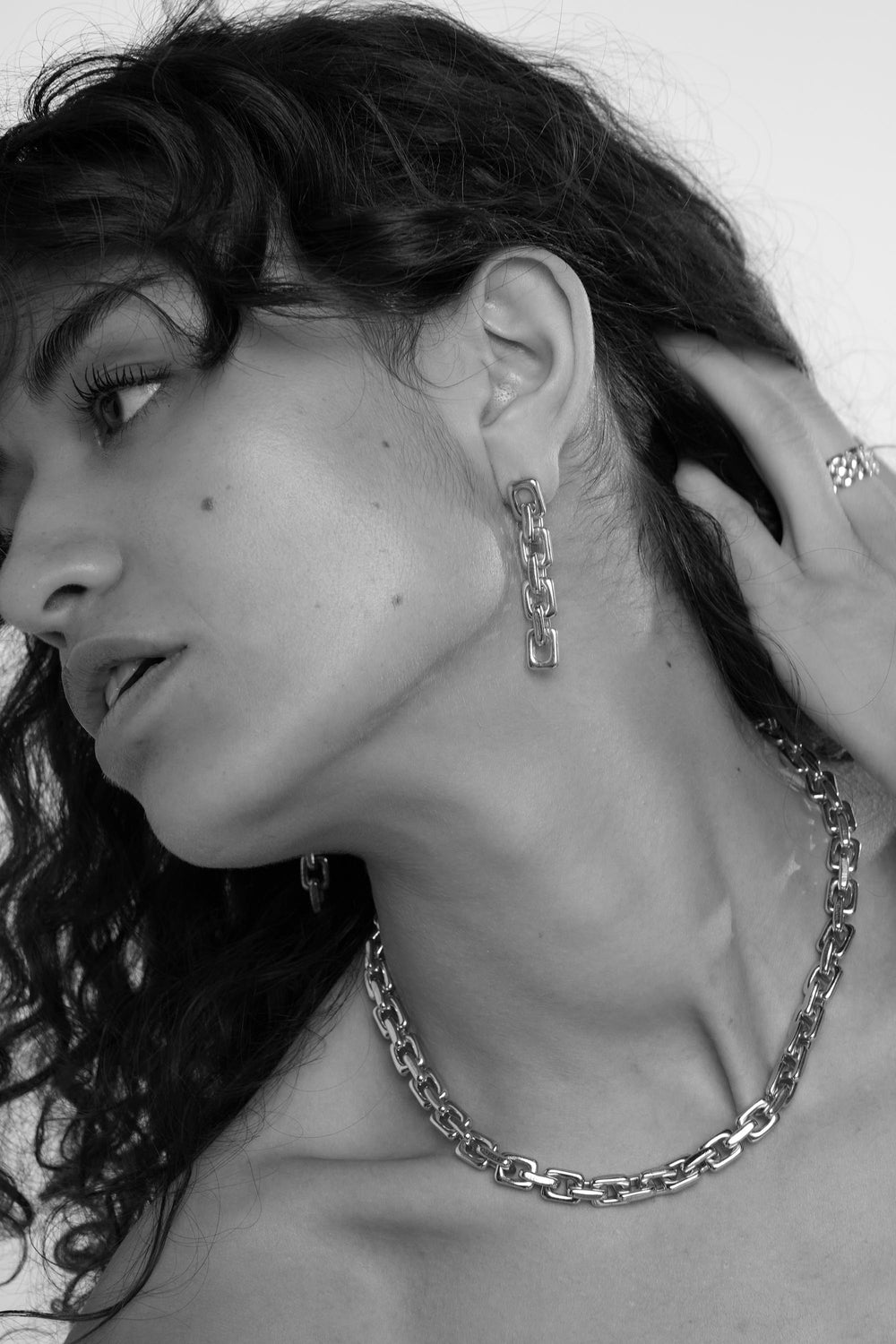 Close-up of a woman wearing a chain necklace and earrings.