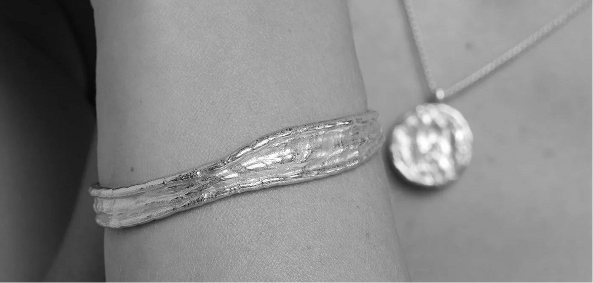 Close-up of a person wearing a silver bracelet and necklace.