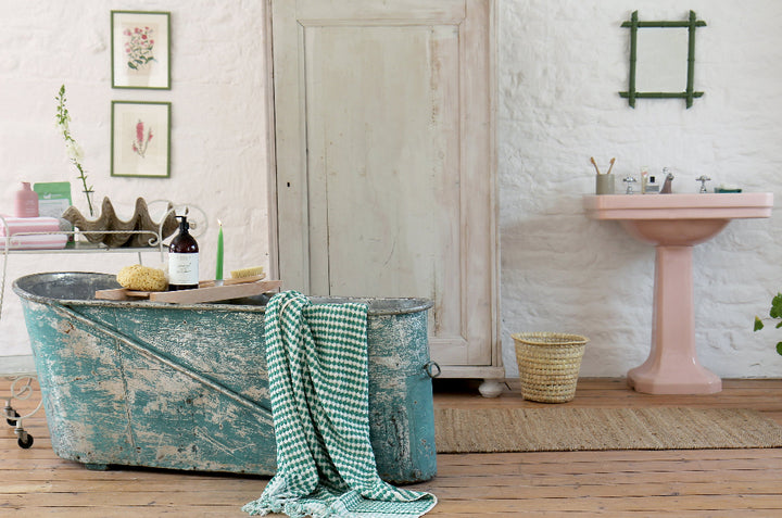 bathroom with vintage metal bath painted in rustic blue paint, clam shell, vintage trolley and botanical prints