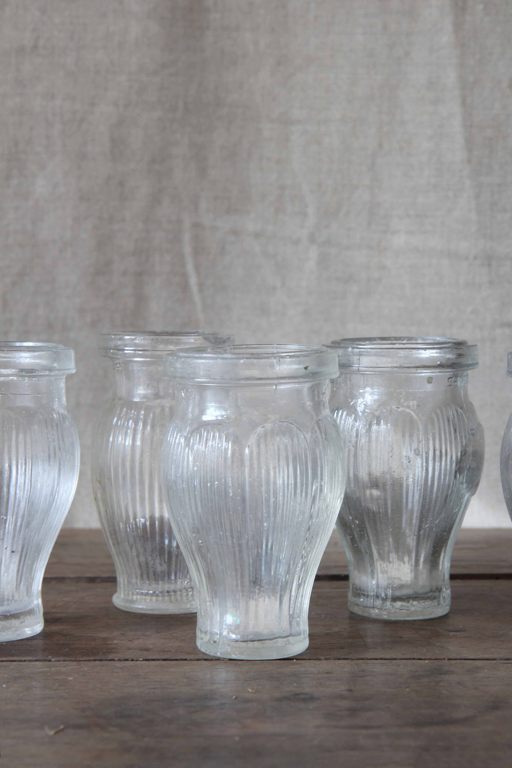 Set of clear glass ribbed paste pots on a wooden surface with a neutral background