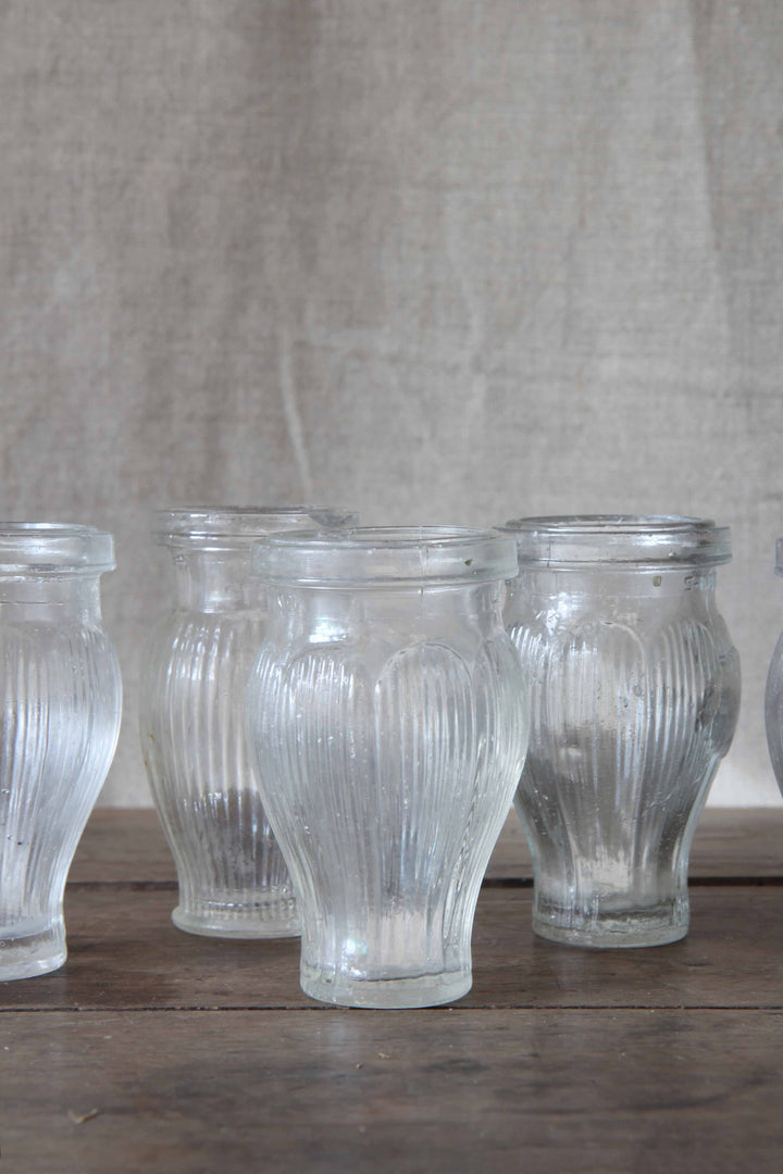 Set of clear glass ribbed paste pots on a wooden surface with a neutral background