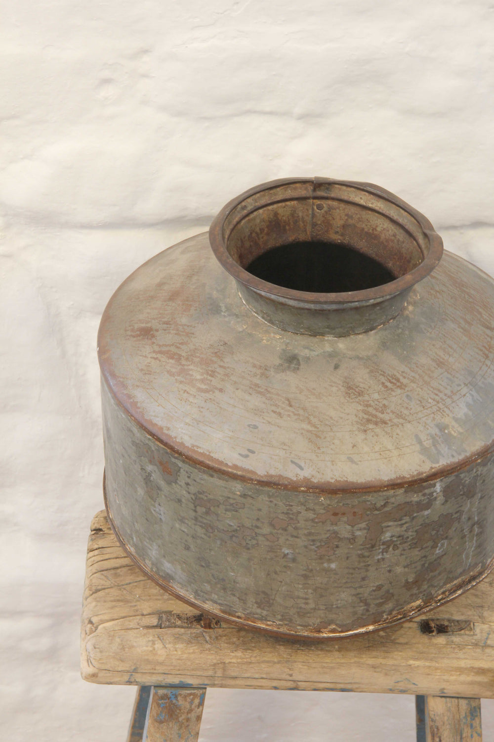 Vintage metal container on a wooden stand with a white background