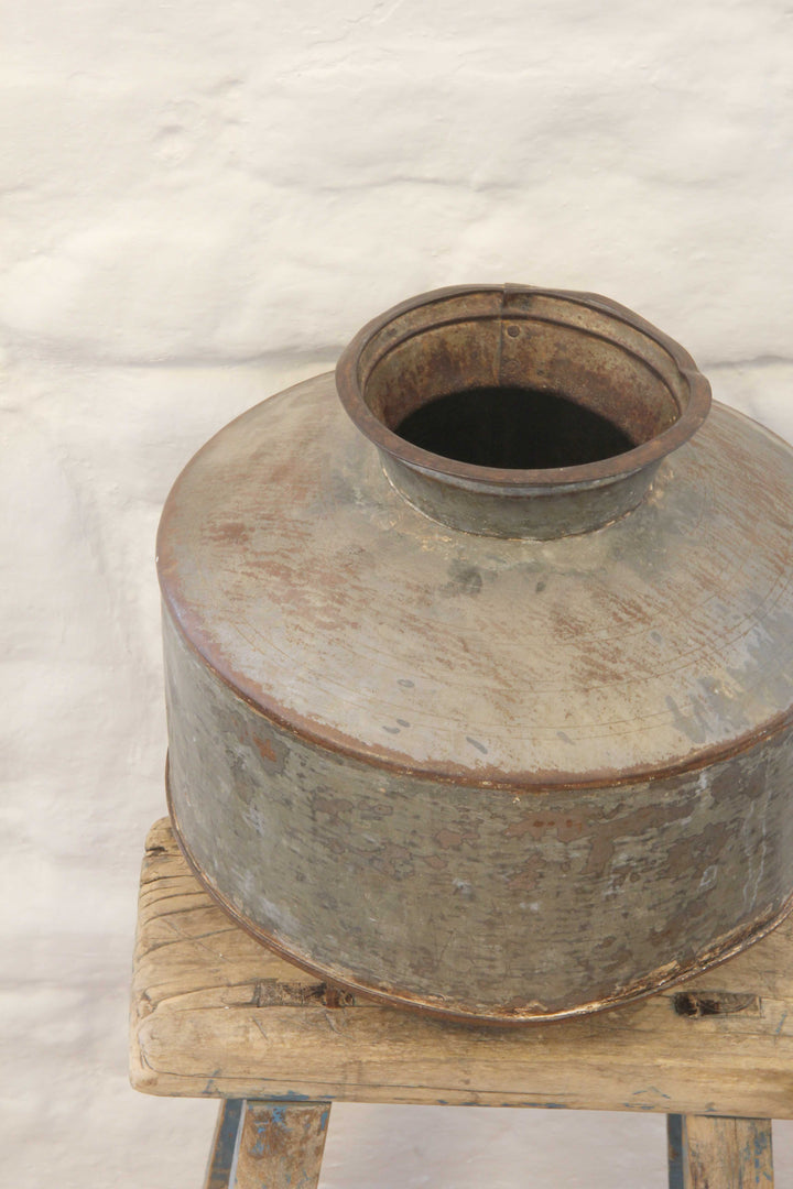 Vintage metal container on a wooden stand with a white background