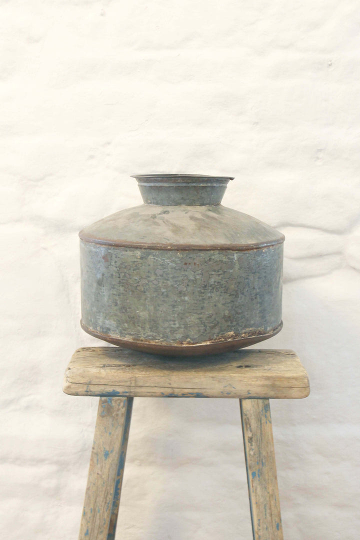 Vintage-style metal water container on a wooden stool against a white background