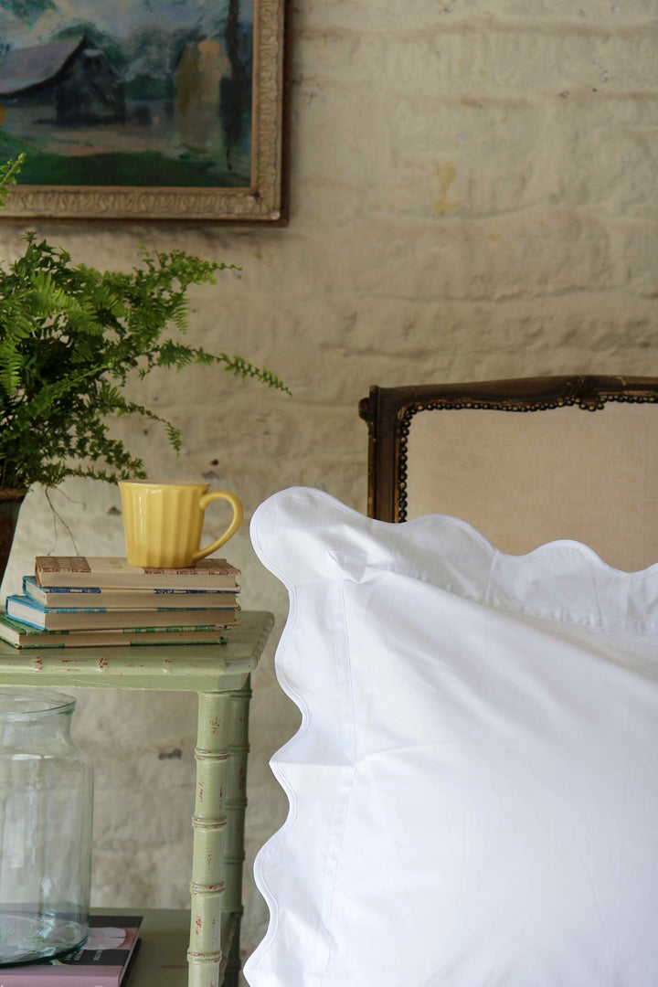 White wiggle pillowcase on bed with vintage bedside table