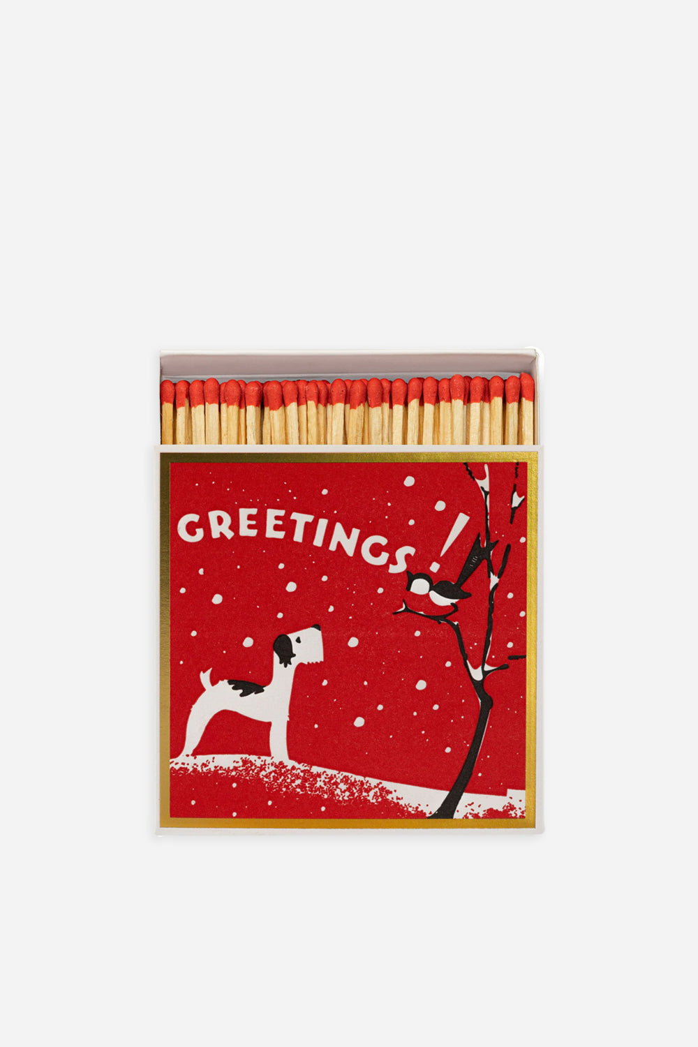 A festive winter-themed box of matches with a red background, featuring a dog, a bird, and a Christmas tree, alongside a box of matches.