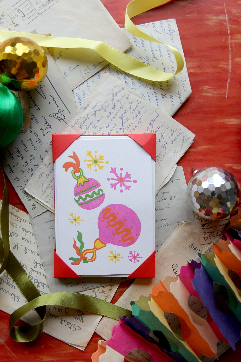 Colorful card with festive designs on a textured surface with ribbons and decorations.
