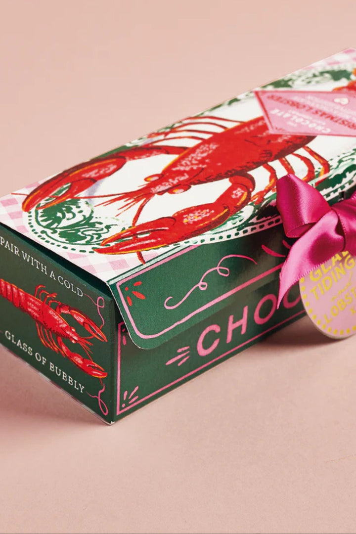 Chocolate box with lobster design and pink bow on a beige background