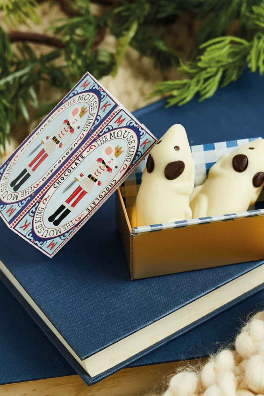 Two white ghost-shaped cookies in a box with a decorative label on a blue surface.