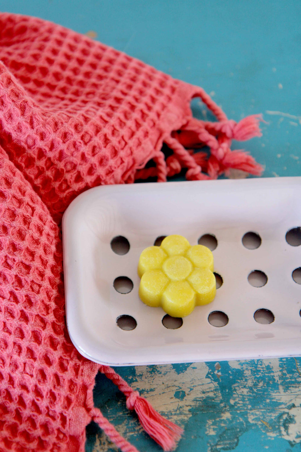 yellow flower soap on pink enamel soap dish