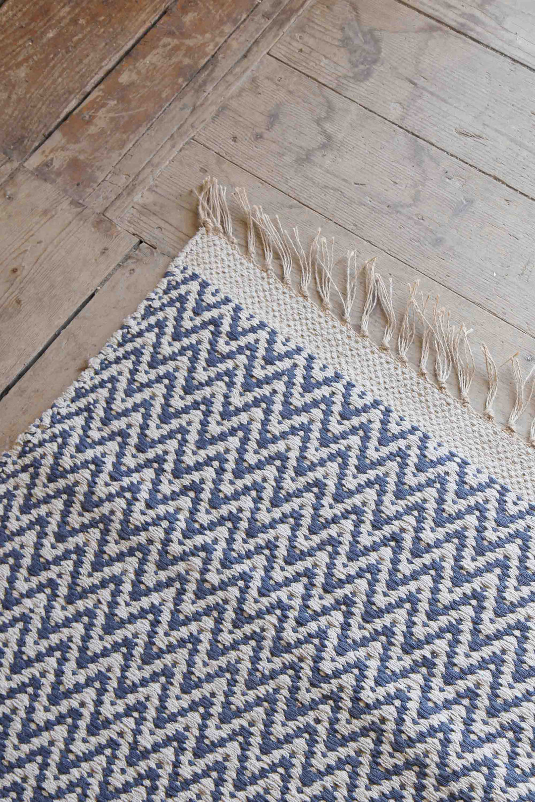 denim blue and cream jute and cotton woven zigzag rug on wooden floor boards