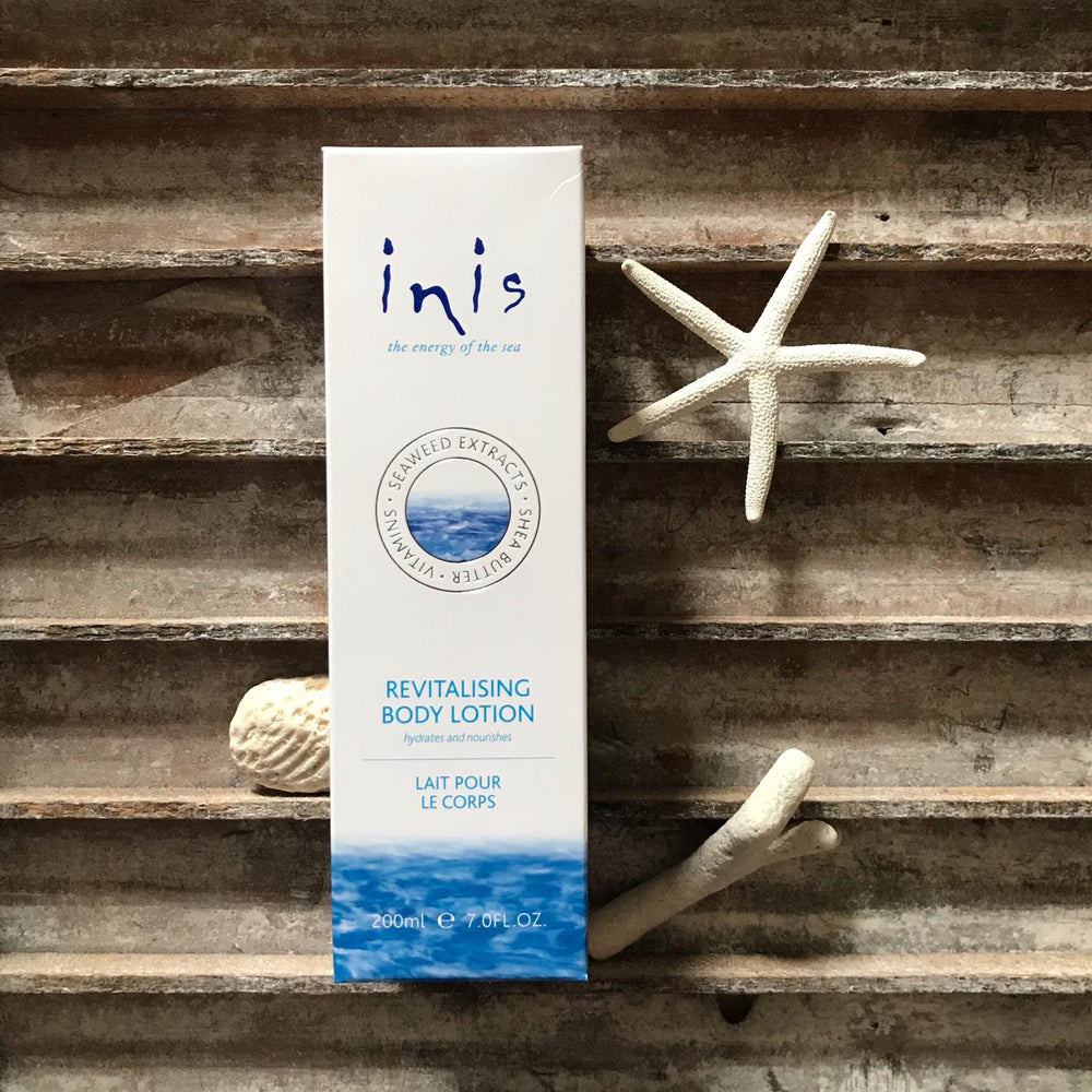 Inis Revitalising Body Lotion on vintage wood background with star fish and shells